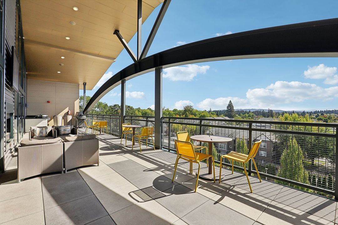 A balcony with a table and chairs overlooking a cityscape.